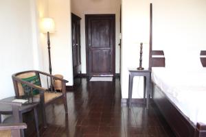 a bedroom with a bed and a chair and a door at Hotel Khamvongsa in Vientiane