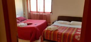 - une chambre avec 2 lits avec des draps rouges et une fenêtre dans l'établissement Bed and breakfast lagiocosa, à Reggio de Calabre