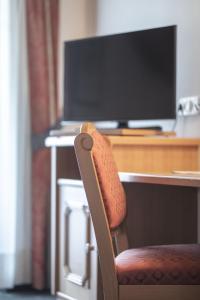 a chair sitting in front of a desk with a television at Hotel Garni Schneider in Lutago
