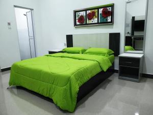 a bedroom with a green bed with a green comforter at Inapdesa Teratak Bonda, Sepri REMBAU in Rembau