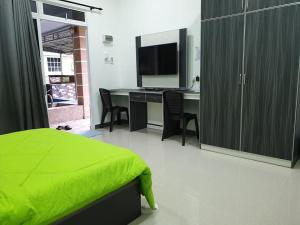 a bedroom with a bed and a desk with a television at Inapdesa Teratak Bonda, Sepri REMBAU in Rembau