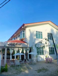 a building with tables and umbrellas in front of it at AAM Hotel in Kota Bharu