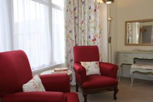 a living room with two red chairs and a mirror at The Cordelia in Scarborough