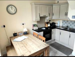 a kitchen with a wooden table and a clock on the wall at The Coach House Douglas in Cork