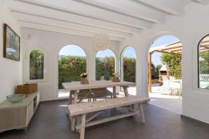 uma sala de jantar branca com uma mesa de madeira e bancos em Ca Sa Mola em Cala Santandria