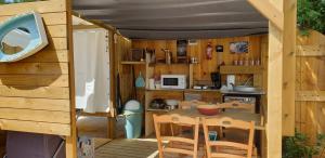 eine Küche mit einem Tisch und Stühlen in einem Haus in der Unterkunft Tente lodge et logement atypique pour 2 à 6 pers aux Mathes La Palmyre in Les Mathes