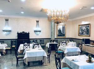 a dining room with white tables and chairs and a chandelier at La Morona Hotel in Morón de la Frontera