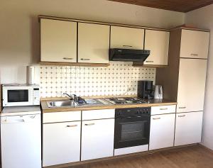 uma cozinha com armários brancos e um forno com placa de fogão em Ferienhaus Haring em Kitzeck im Sausal
