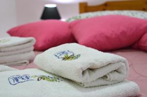 ネア・プラギアにあるAntony Apartmentsのピンクの枕が付いたベッドの上にタオルを積み重ねる