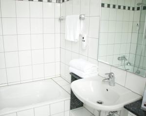 a white bathroom with a sink and a bath tub at Z&B Hotel in Trier