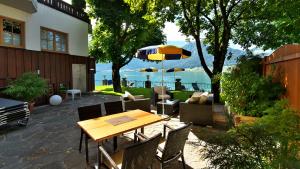 eine Terrasse mit einem Tisch, Stühlen und einem Sonnenschirm in der Unterkunft Hotel Weisser Hirsch in St. Wolfgang