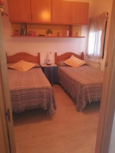 1 dormitorio con 2 camas y mesa con lámpara en Casa Simona, en Navas de Estena