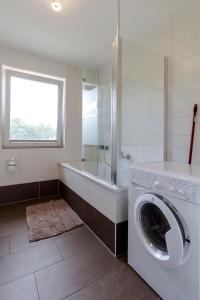 a bathroom with a washing machine and a bath tub at Pension am See in Kremmen