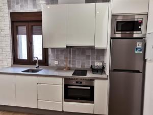 uma cozinha com armários brancos e um frigorífico de aço inoxidável em Vivienda Turística Cumbre de Pontones em Pontones