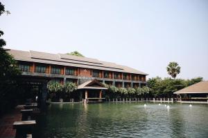 um edifício com um lago em frente em Hotel de l'amour SHA PLUS em Prakhon Chai