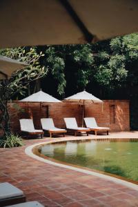 a patio with chairs and umbrellas and a pool at Hotel de l'amour SHA PLUS in Prakhon Chai
