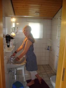 une femme debout dans une salle de bains avec lavabo dans l'établissement Schäferei Bährs, à Neufelderkoog