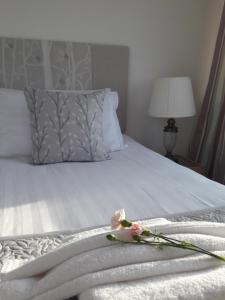 a bed with white sheets and a flower on it at Seren Villa in Llandudno
