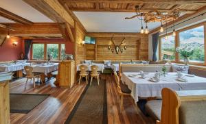 un restaurante con mesas y sillas blancas y ventanas en Sportpension Enzian, en Saalbach Hinterglemm