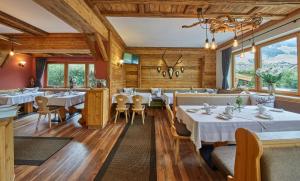 a restaurant with white tables and chairs and windows at Sportpension Enzian in Saalbach-Hinterglemm
