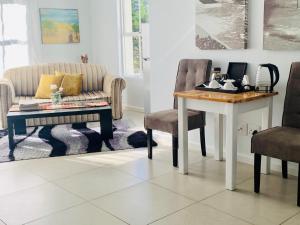 a living room with a table and a couch at Abington Manor Fish Hoek Guesthouse in Fish Hoek