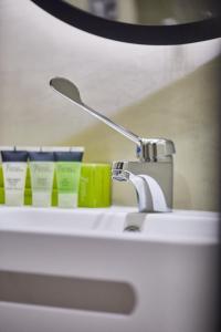 a bathroom sink with a faucet and products on it at Silken Coliseum in Santander