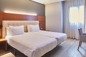 a hotel room with two beds and a window at Silken Coliseum in Santander