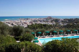 a swimming pool with umbrellas and chairs and the ocean at Residence Chiesiola in Vieste