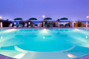 a large swimming pool at night with chairs and umbrellas at Residence Chiesiola in Vieste
