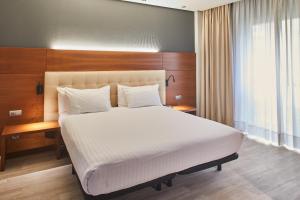 a bedroom with a large white bed and a desk at Silken Coliseum in Santander