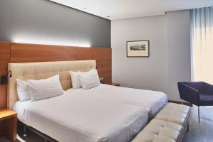 a hotel room with a bed and a chair at Silken Coliseum in Santander