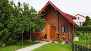 drewniany dom z werandą i ogrodzeniem w obiekcie Domki Żabi Staw w mieście Mikołajki