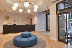 a lobby with a blue ottoman in front of a reception at Silken Coliseum in Santander