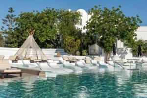 uma piscina com espreguiçadeiras e uma piscina em AMĀRIA Beach Resort by NOMÉE Hospitality Group em Kamari