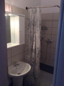 uma casa de banho com um lavatório e um chuveiro com um espelho. em Pension Karadolas Rachoni em Skala Rachoniou