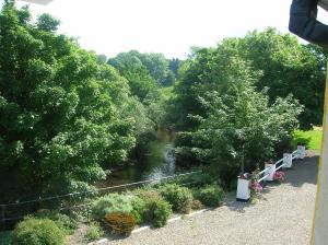 a view of a river with benches and trees at Riverbank Cottages in Scarriff