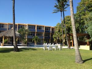 a building with a table and chairs and palm trees at Hotel Calli in Santo Domingo Tehuantepec