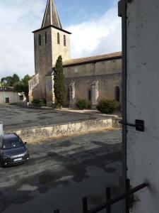 a church with a car parked in a parking lot at Au Cœur de Ménestérol in Montpon-Ménestérol