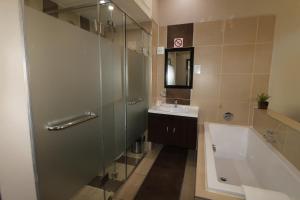 uma casa de banho com um chuveiro, um lavatório e uma banheira em Alcazaba Lodges em Joanesburgo