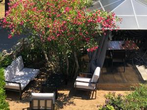 un patio con sillas, una mesa y flores rosas en Rez de Villa Pébrier en Fréjus