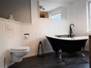 a bathroom with a black tub and a toilet at Old School på Eidslandet - exclusive apartment in Eidslandet