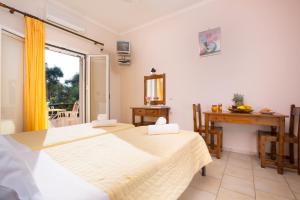 een slaapkamer met 2 bedden, een tafel en een raam bij Odysseus Apartments By Hotelius in Agios Gordios