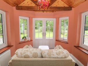 ein Schlafzimmer mit orangefarbenen Wänden und Fenstern sowie einem Sofa in der Unterkunft Bawbee Cottage in Denbigh