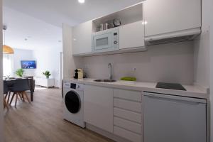 a white kitchen with a sink and a dishwasher at Luxor Torre del Clavero Apartments in Salamanca