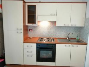 cocina con armarios blancos, fogones y fregadero en Appartamento indipendete VillaRosa, en Alba Adriatica