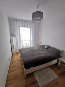 a white bedroom with a bed and a window at Biała Perła Apartment in Gdańsk