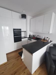 a kitchen with white cabinets and a black counter top at Biała Perła Apartment in Gdańsk