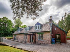 een oud stenen huis met een rode schuur bij Coylumbridge Cottage in Aviemore