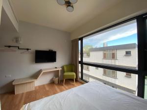 ein Schlafzimmer mit einem Bett und einem großen Fenster in der Unterkunft IF Guest House in Tainan