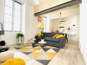 a living room with a blue couch and yellow pillows at Feel@Home Nemausus « Le 4 » in Nîmes